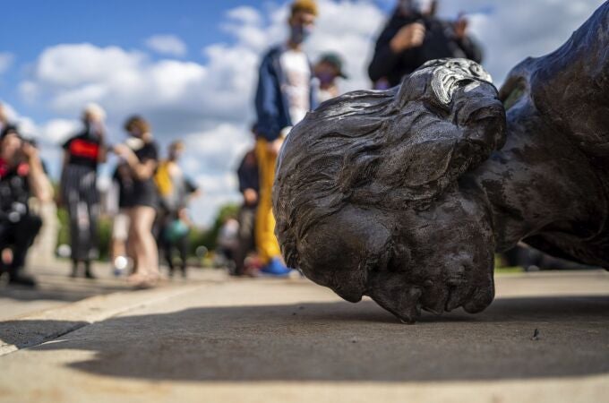 Varias personas observan una estatua derribada de Colón en Estados Unidos