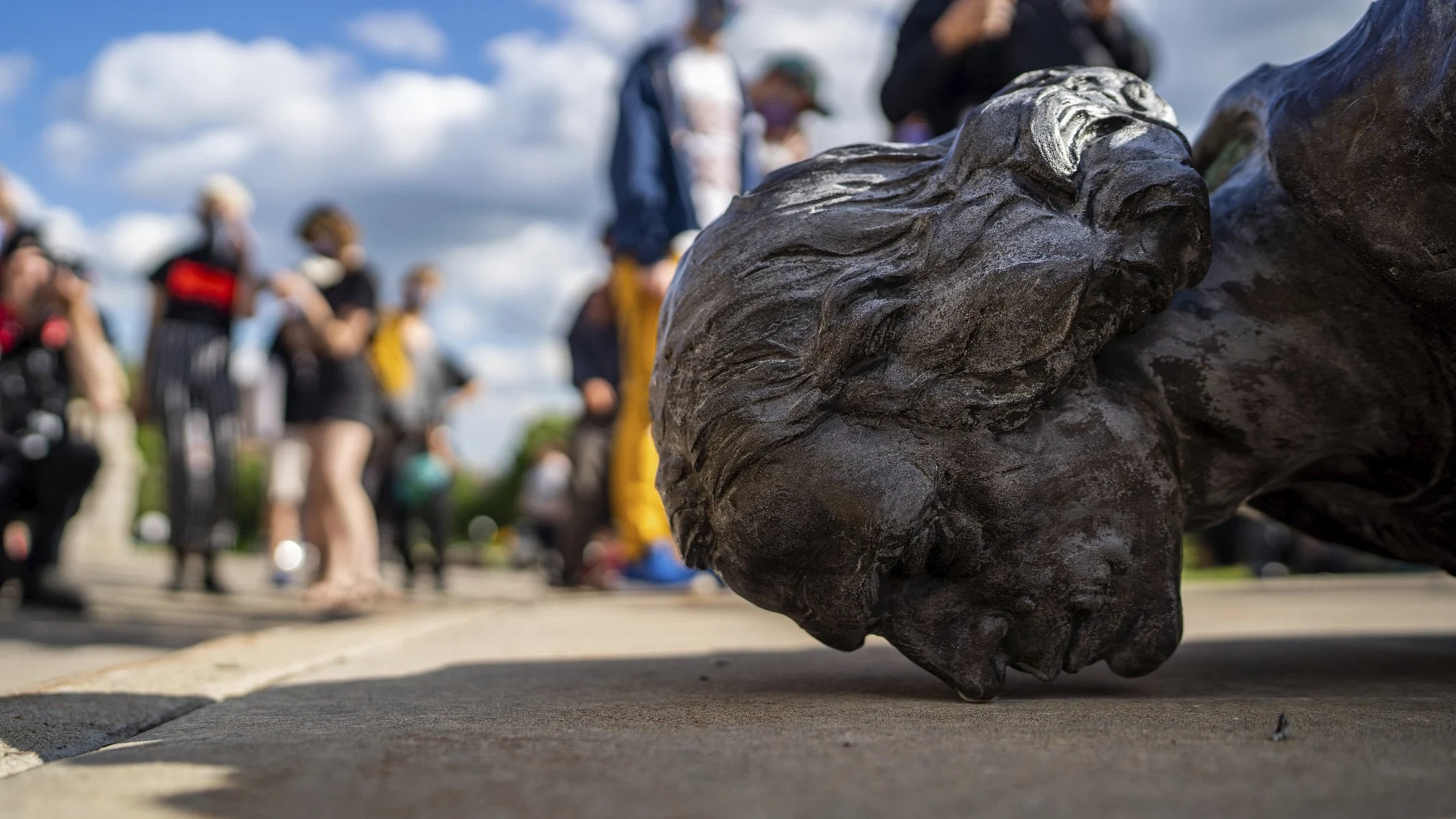 Varias personas observan una estatua derribada de Colón en Estados Unidos