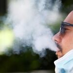 Un hombre expulsa el humo del tabaco mientras fuma sentado en una calle en Córdoba. EFE/Salas