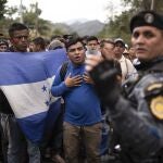 FILE - In this Jan. 16, 2020 file photo, Honduran migrants walking in a group stop before Guatemalan police near Agua Caliente, Guatemala, on the border with Honduras. In a report released Tuesday, Oct. 13, 2020, by the Democratic staff of a U.S. Senate committee says U.S. immigration agents assigned to Guatemala to advise local authorities violated terms of their funding by helping officials deport Hondurans traveling in a migrant caravan early this year. (AP Photo/Santiago Billy, File)