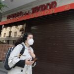 Una mujer pasa por el establecimiento cerrado del Museo del Jamón en la calle Mayor, 7, en Madrid (España)