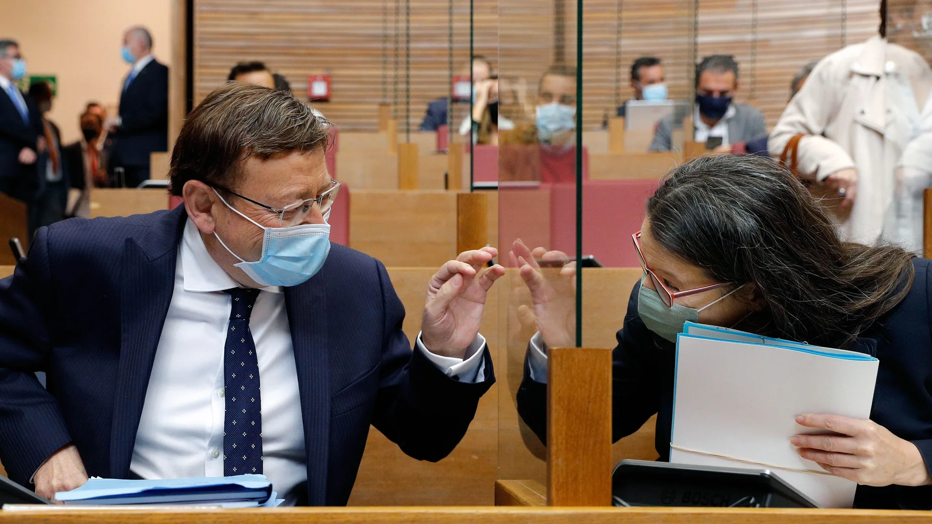 El presidente de la Generalitat, Ximo Puig,y la vicepresidenta, Mónica Oltra, se saludan separados por un cristal protector en el hemiciclo de Las Cortes Valencianas