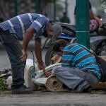 AME2555. CARACAS (VENEZUELA), 20/10/2020.- Dos hombres desarman una poceta en un basurero el 15 de octubre de 2020, en Caracas (Venezuela). Hay que pararse y releer para poder imaginar la dimensión de algunas cifras: en Venezuela, la inflación de los alimentos durante la cuarentena alcanzó el 671,8 %. La traducción a las calles es pobreza y desnutrición, un drama cotidiano que marca y atenaza más que nunca a los ciudadanos. Ir al mercado es sinónimo de llevarse una sorpresa. Si un ciudadano va dos veces en la misma semana, los productos de la cesta básica tendrán precios distintos. EFE/ Miguel Gutiérrez