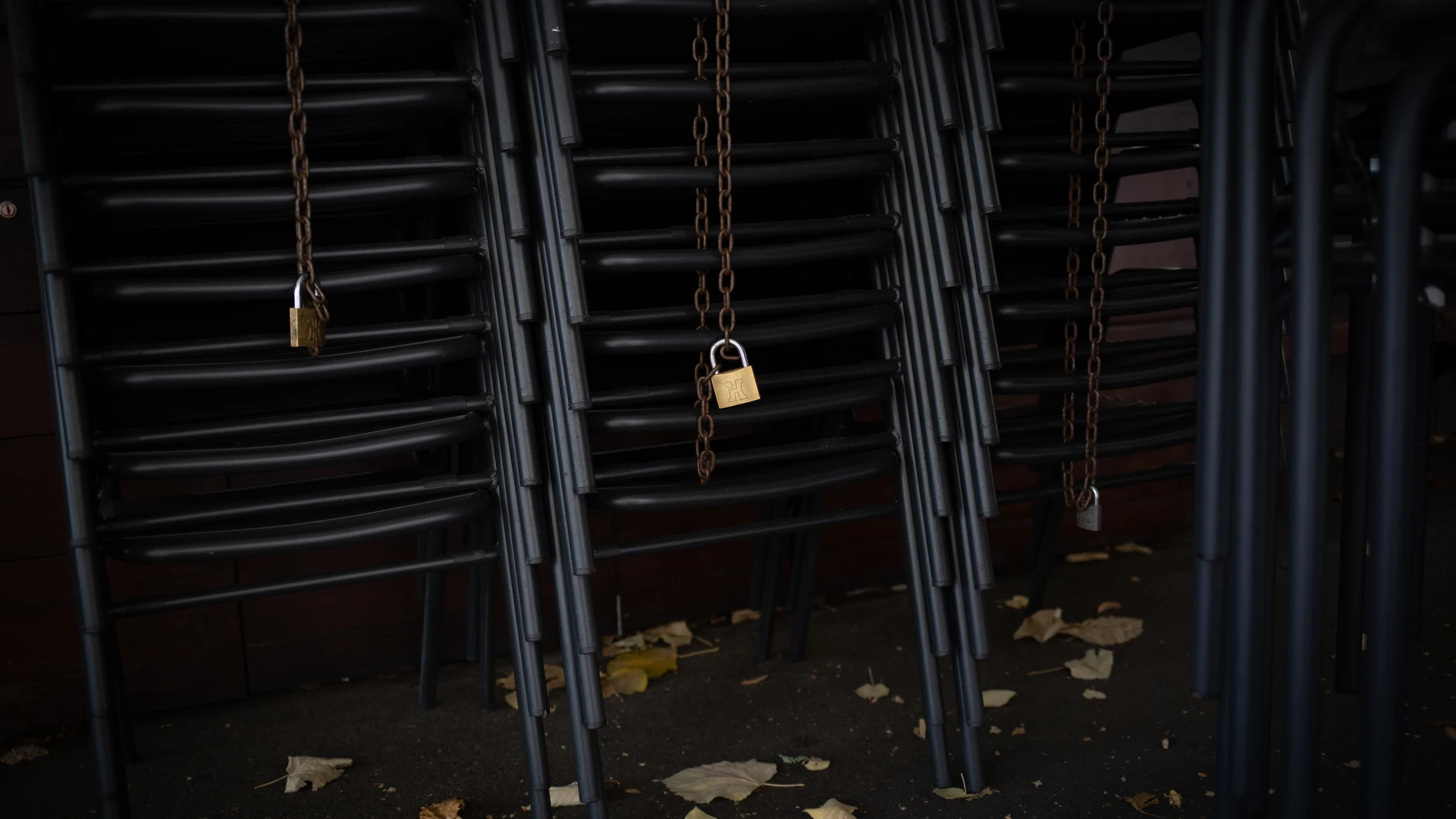Candados en las sillas de una terraza de un bar cerrado