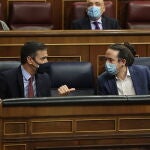 El presidente del Gobierno, Pedro Sánchez (i); y el vicepresidente segundo del Gobierno, Pablo Iglesias, mantienen una conversación durante el pleno en el que se debate la moción de censura planteada por Vox, en el Congreso de los Diputados