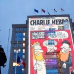 Un agente de Policía observa la proyección de caricaturas del periódico satírico francés "Charlie Hebdo" en edificios del centro de Montpellier, el año pasado