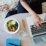 En la imagen, una mujer come una rica ensalada mientras trabaja.