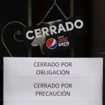 VALLADOLID, 06/11/2020.- Desde esta medianoche y durante 14 días Castilla y León tendrá cerrada la hostelería, restauración y centros comerciales, y los centros deportivos cerrados, y no se podrán visitas las residencias, medidas que se suman al cierre perimetral de la Comunidad y el toque de queda entre las diez de la noche y las 6 de la mañana. Un cartel anuncia el cierre en un bar de Valladolid, este viernes. EFE/NACHO GALLEGO