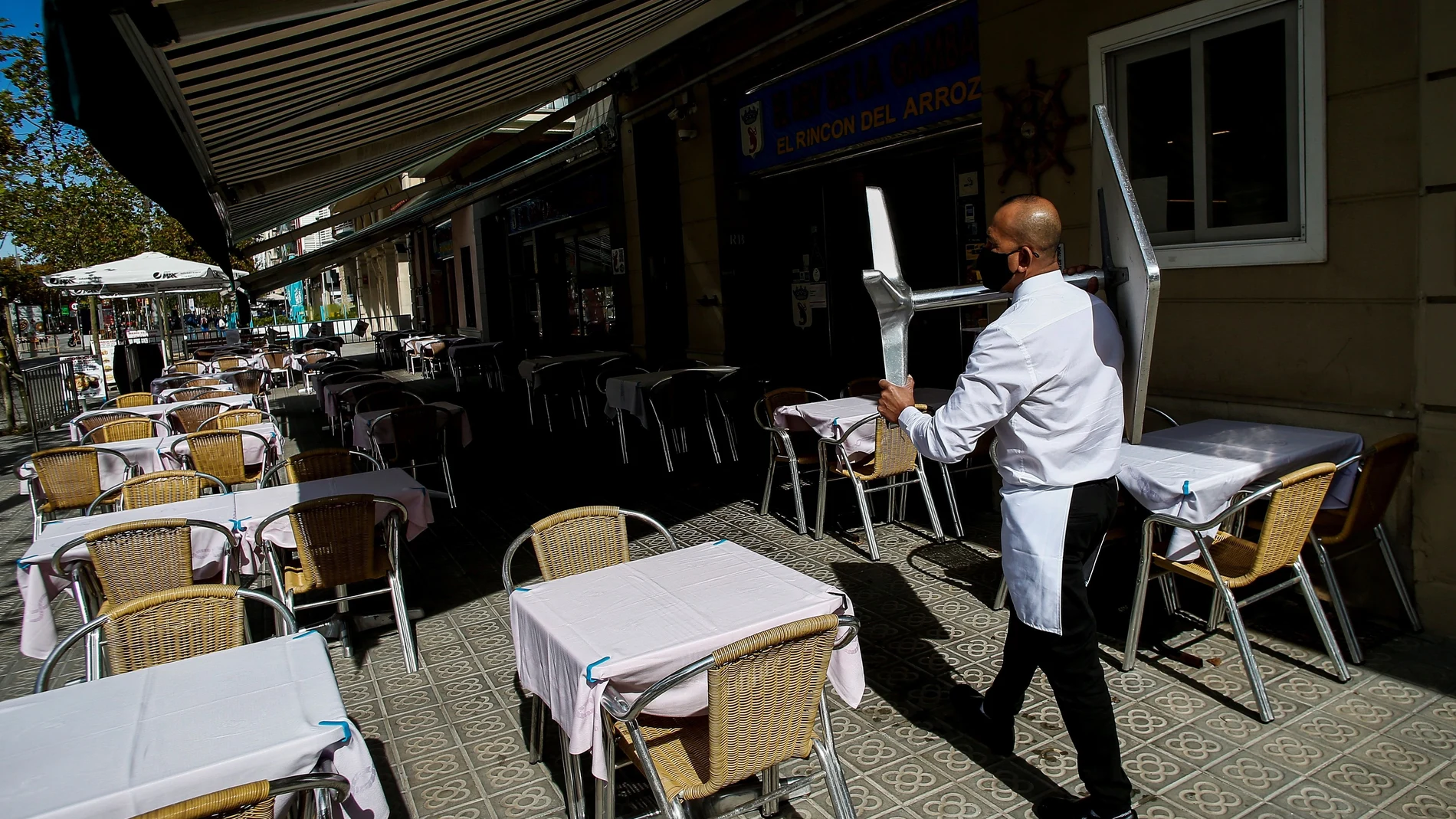 Un camarero recoge una mesa en un restaurante del barrio de la Barceloneta de Barcelona