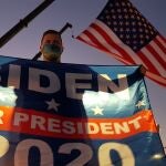 Un joven sostiene un banderín electoral de Joe Biden para presidente 2020 mientras espera su llegada para ofrecer el discurso de victoria