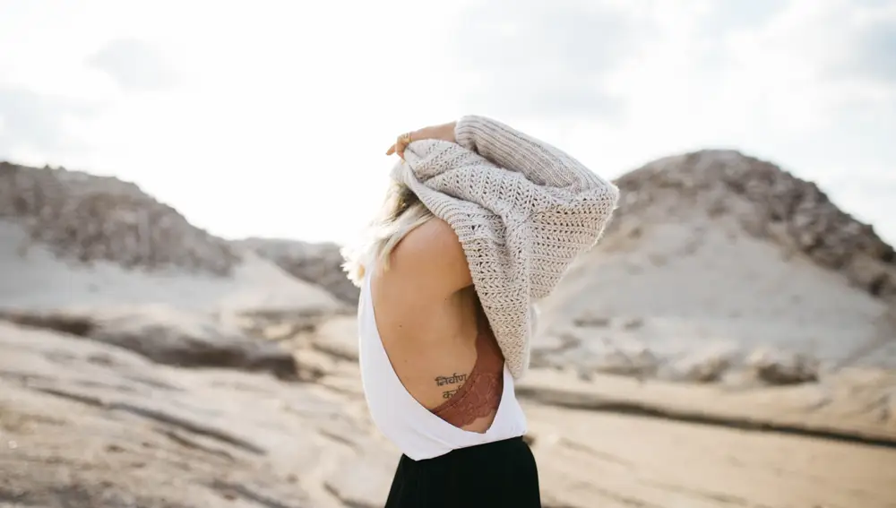 En la imagen, una chica deja ver su tatuaje mientras se pone un jersey