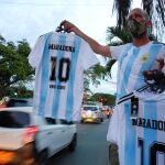 Un hombre vende camisetas del exfutbolista Diego Armando Maradona en una calle, hoy en Cali (Colombia).