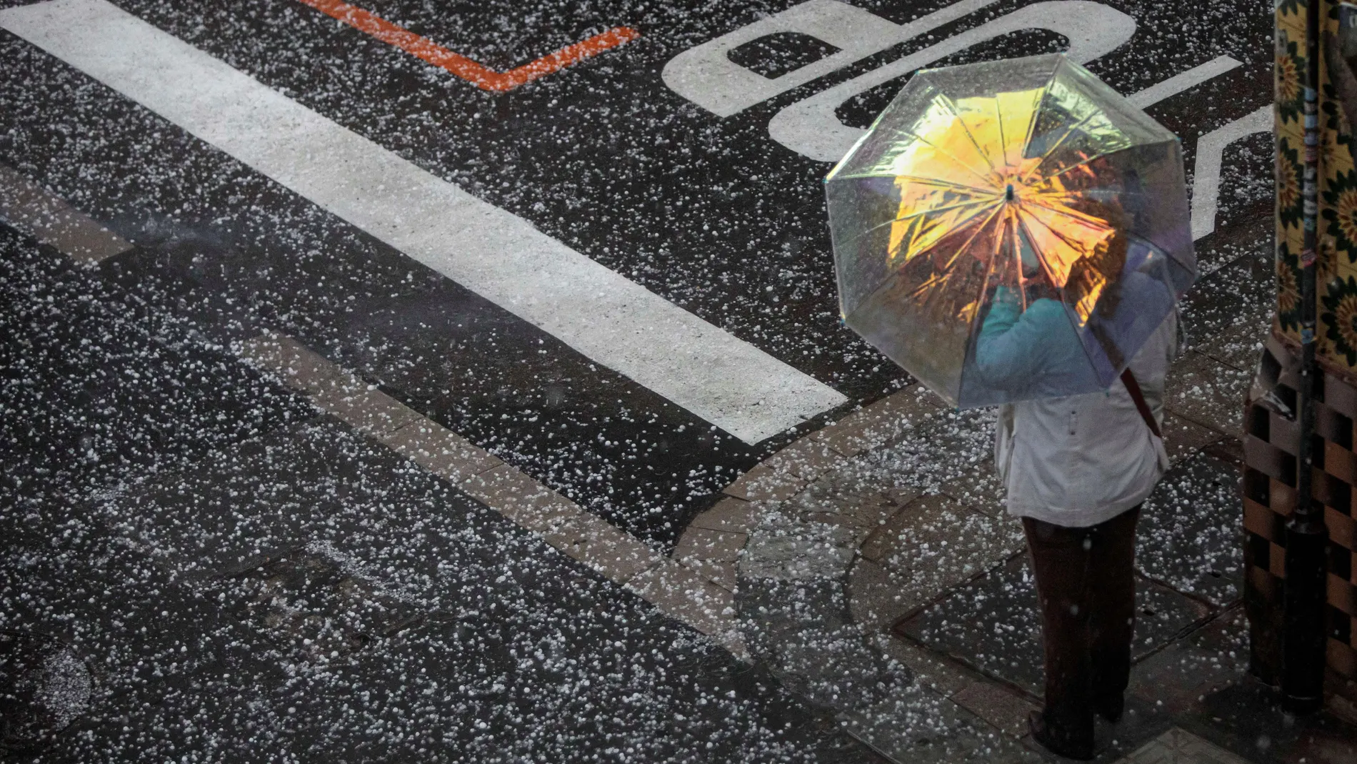 Una persona se protege del granizo con un paraguas este viernes en la ciudad de Valencia.