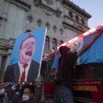A protester holds up a painting depicting President Alejandro Giammattei during a protest demanding his resignation, in Guatemala City, Saturday, Nov. 28, 2020. Protests continue against Giammattei and the legislature for approving a budget that cut educational and health spending. Guatemala's Congress backed down on Monday on the proposed federal budget. (AP Photo/Moises Castillo)