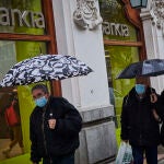 Ciudadanos pasando por delante de una oficina bancaria en estos tiempos de coronavirus en los que ha aumentado la morosidad en los prestamos bancarios