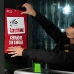 Un trabajador de hostelería coloca un cartel donde se lee "Nos arruinan. Cerrados sin ayudas"