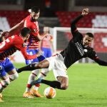 El delantero del PSV, Donyell Malen (d), cae ante los jugadores del Granada, Carlos Neva (i) y el francés, Maxime Gonalons, durante el encuentro correspondiente a la fase de grupos de la Liga Europa en el estadio Nuevo Los Cármenes, en Granada. EFE / Miguel Ángel Molina.