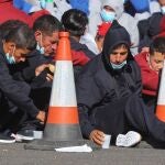 Varios inmigrantes descansan en el muelle de Arguineguín tras ser rescatados por Salvamento Marítimo