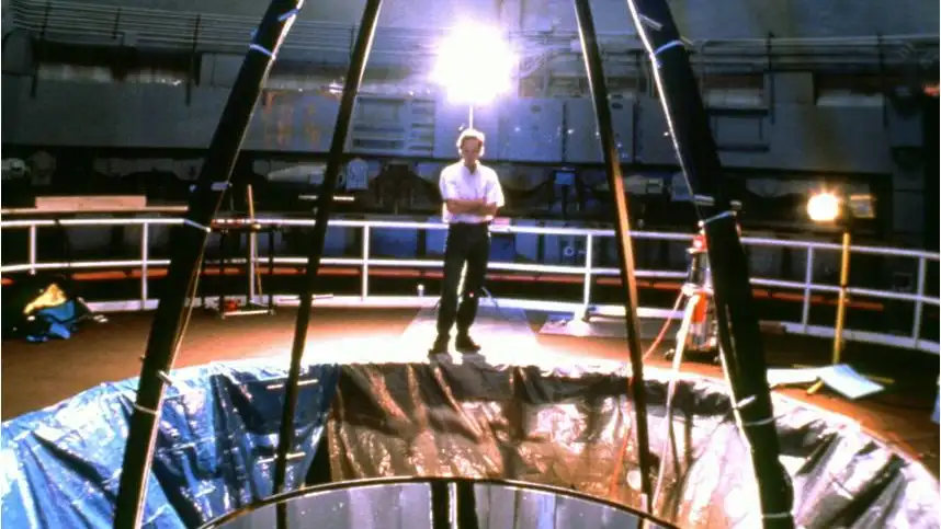 Una imagen del segundo prototipo de telescopio con espejo líquido, el Liquid Mirror Telescope de la NASA. Estuvo en funcionamiento entre los años 1995 y 2002, tenía un espejo de tres metros de diámetro y se utilizó para monitorizar basura espacial. La luz entra por la parte superior, se refleja en el espejo y es dirigida al sensor, que es el dispositivo montado arriba, sobre las patas de araña.