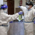 Una trabajadora desinfecta a un médico tras finalizar su jornada