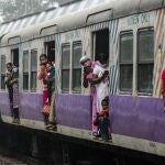 Stranded commuters of a local train look out as supporters of left parties block a train track during a nationwide shutdown called by thousands of Indian farmers protesting new agriculture laws, in Kolkata, India, Tuesday, Dec. 8, 2020. The strike follows five rounds of talks between the farmers and the Indian government that have failed to produce any breakthroughs. (AP Photo/Bikas Das)