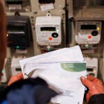 Una persona lee la factura de la luz frente a los contadores
