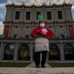 Manoli Sevilla, de 82 años, posa en el teatro real con una capa roja y un árbol de navidad como sombrero