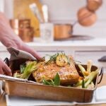 En la imagen, un hombre sacando un suculento plato del horno.