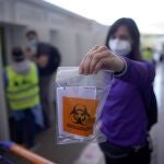 Un argentino muestra una bolsa de plástico con una muestra de saliva para una prueba de covid-19