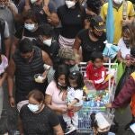 Pedestrians wearing face masks amid the COVID-19 pandemic walk in the Mesa Redonda Market, a popular spot for Christmas shopping in Lima, Peru, Friday, Dec. 18, 2020. Peru's Health Ministry has announced on Tuesday, Dec. 22, that it has surpassed 1 million confirmed cases of the new coronavirus. (AP Photo/Martin Mejia, File)