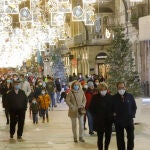 Transeúntes pasean bajo las luces navideñas, llevando mascarilla, en Vigo, Galicia (España), a 25 de diciembre de 2020