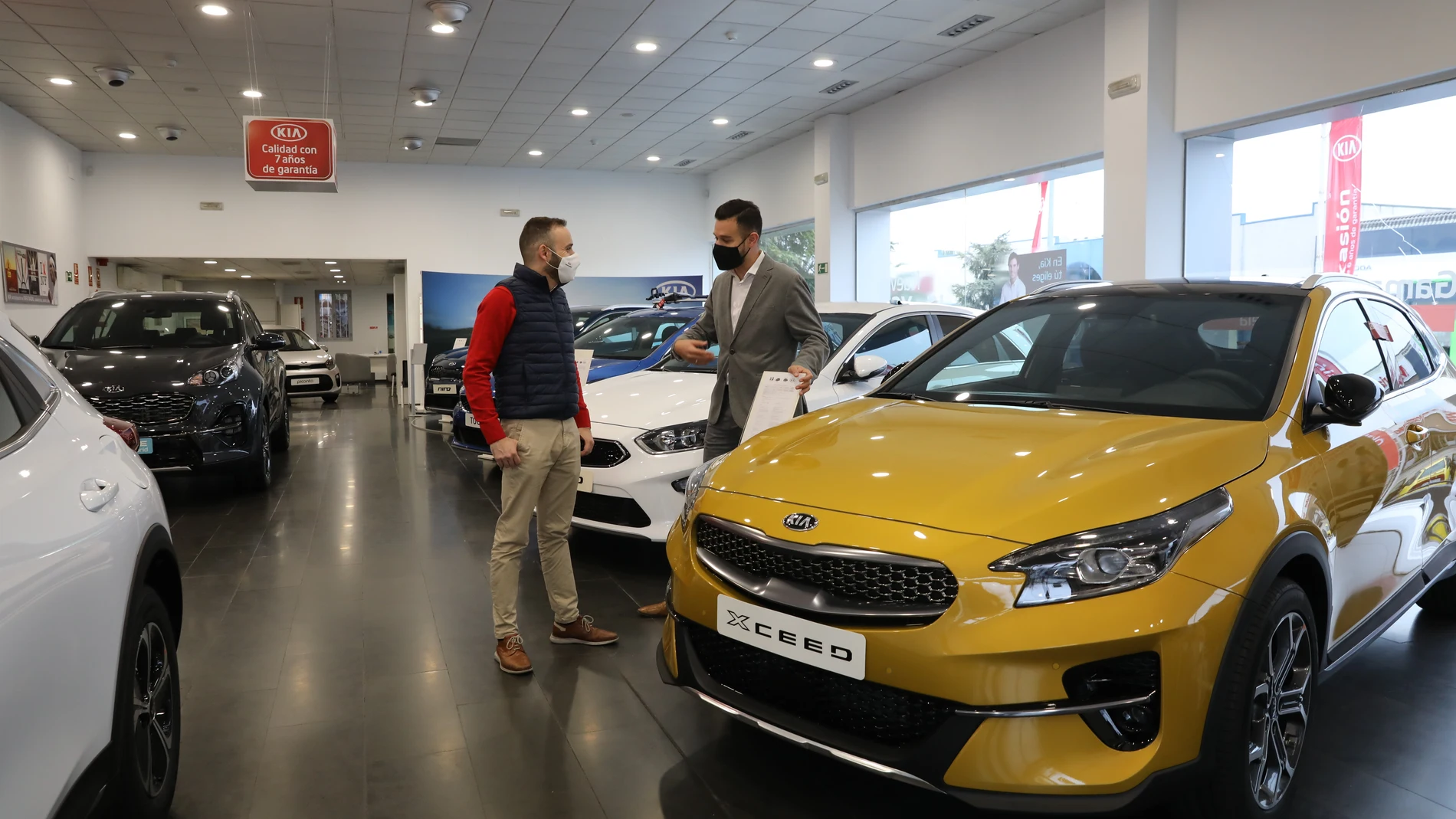 Un empleado de un concesionario de coches muestra un coche a un cliente