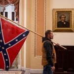 Uno de los seguidores de Donald Trump que irrumpieron en el Capitolio y que pasa por delante de uno de los retratos que se conservan en su interior