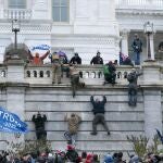 Partidarios del presidente Donald Trump escalan el muro oeste del Capitolio de Estados Unidos el miércoles 6 de enero