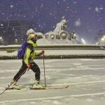 Una persona avanza con esquíes junto a la fuente de Cibeles, cubierta de nieve por la borrasca Filomena, el pasado enero