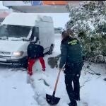 Un guardia civil, pala en mano, ayuda a una furgoneta atrapada en la nieve en Escalona (Toledo)