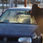 Imagen de archivo de una mujer quitando el hielo de su coche