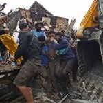Un grupo de jóvenes rescata a un hombre que se había quedado bajo los escombros de un edificio gubernamental tras el terremoto en Mamuju, Indonesia