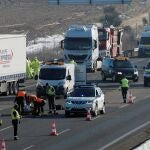 Agentes de la Guardia Civil junto al cuerpo sin vida de uno de los conductores de tres camiones que han fallecido en la A-6, en Tordesillas (Valladolid), tras ser atropellados por un cuarto camión, cuando intentaban apagar el incendio que se había producido en uno de los articulados