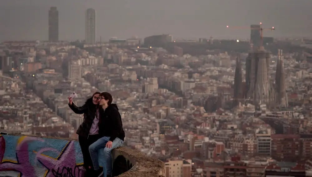 Una pareja se fotografía. Al fondo, la Sagrada Familia. Y más al fondo, el Hotel Arts y la Torre Mapfre.