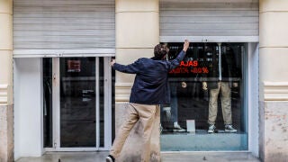 El propietario de un comercio cierra su establecimiento el primer día del cierre total de la hostelería y de tiendas a las 18.00h en Valencia El propietario de un comercio cierra su establecimiento el primer día del cierre total de la hostelería y de tiendas a las 18.00h en Valencia