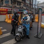 Un voluntario comprueba el código sanitario que certifica que no se tiene covid-19 a un motorista en Wuhan
