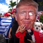 Una persona sostiene una máscara con la imagen del presidente Donald Trump mientras espera su llegada este miércoles en West Palm Beach