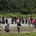 Migrants cross the Tuquesa river after a trip on foot through the jungle to Bajo Chiquito, Darien province, Panama, Wednesday, Feb. 10, 2021. Bajo Chiquito is the first population center that migrants coming from the Colombian border see when they cross over after several days of slogging through the jungle into Panama. (AP Photo/Arnulfo Franco)