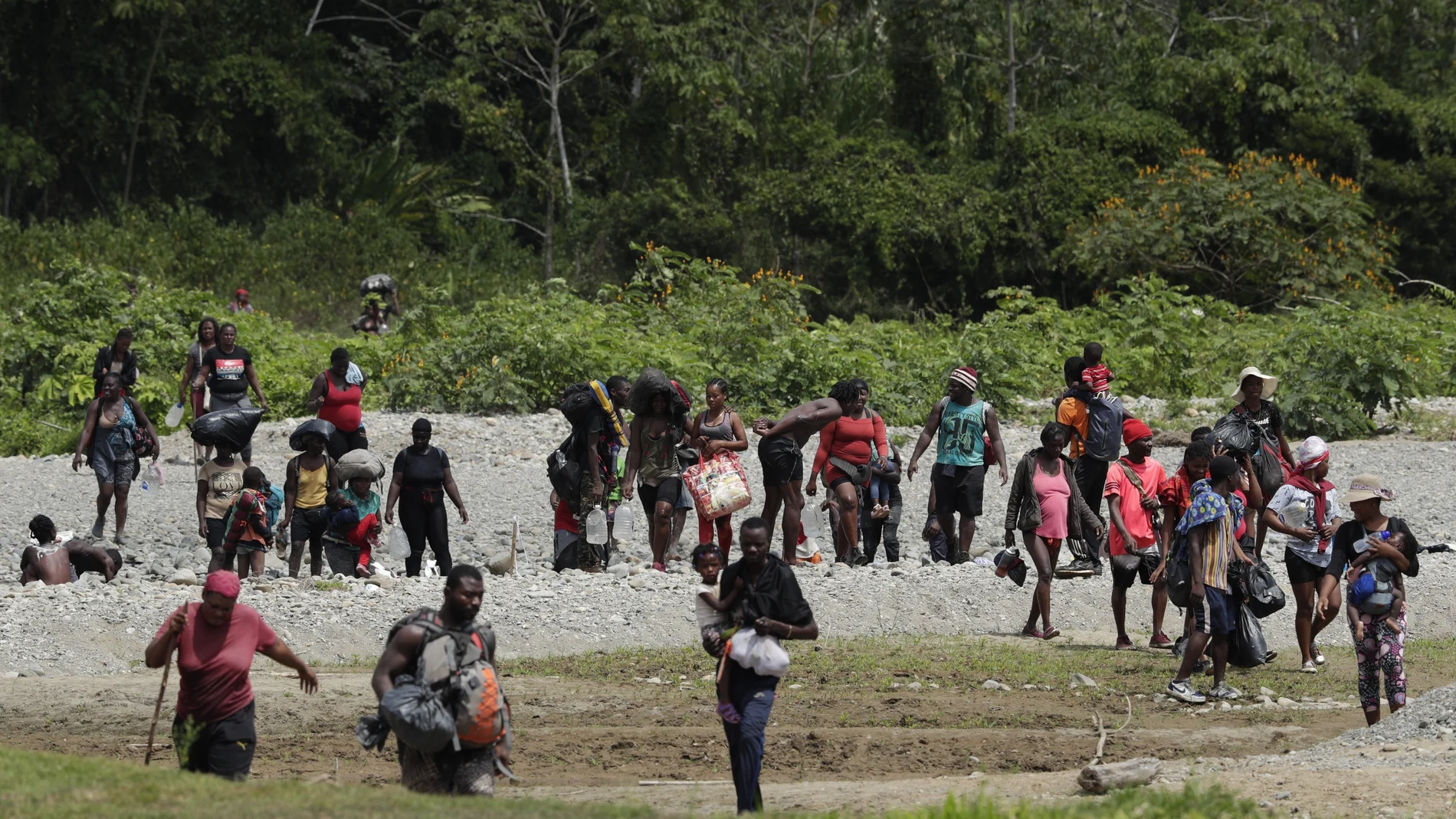 Migrants cross the Tuquesa river after a trip on foot through the jungle to Bajo Chiquito, Darien province, Panama, Wednesday, Feb. 10, 2021. Bajo Chiquito is the first population center that migrants coming from the Colombian border see when they cross over after several days of slogging through the jungle into Panama. (AP Photo/Arnulfo Franco)
