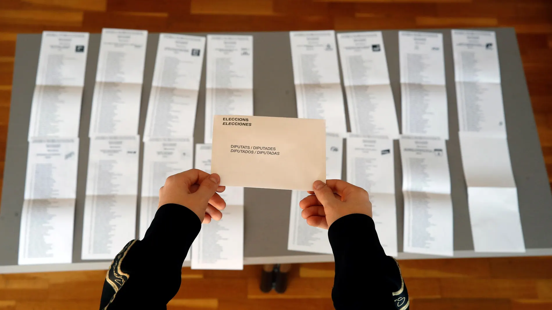 Una persona coge un sobre para las elecciones al Parlamento de Cataluña 2021