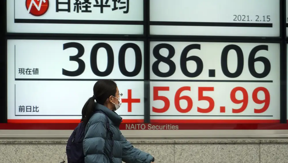 Una mujer camina frente a un distintivo de Nikkei en Japón