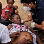 LIM01. MADRE DE DIOS (PERÚ) 16/02/2021. Una mujer embarazada recibe ayuda hoy, martes después de incidentes de las autoridades con un grupo de inmigrantes que cruzaron la frontera provenientes de Brasil, en la localidad de Iñapari, Madre de Dios, Perú. Aproximadamente 350 haitianos cruzaron el Puente de la Amistad desde Brasil, para ingresar a Perú, lo que produjo incidentes entre las autoridades peruanas y grupos de personas, entre ellas numerosas mujeres y niños que cruzaron irregularmente la frontera. EFE/Paolo Peña