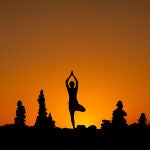 Una persona realiza una sesión de yoga durante un amanecer en Playa del Duque (Tenerife)
