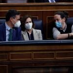 El presidente del Gobierno, Pedro Sánchez (i), conversa con sus vicepresidentes Carmen Calvo, y Pablo Iglesias durante un Pleno del Congreso